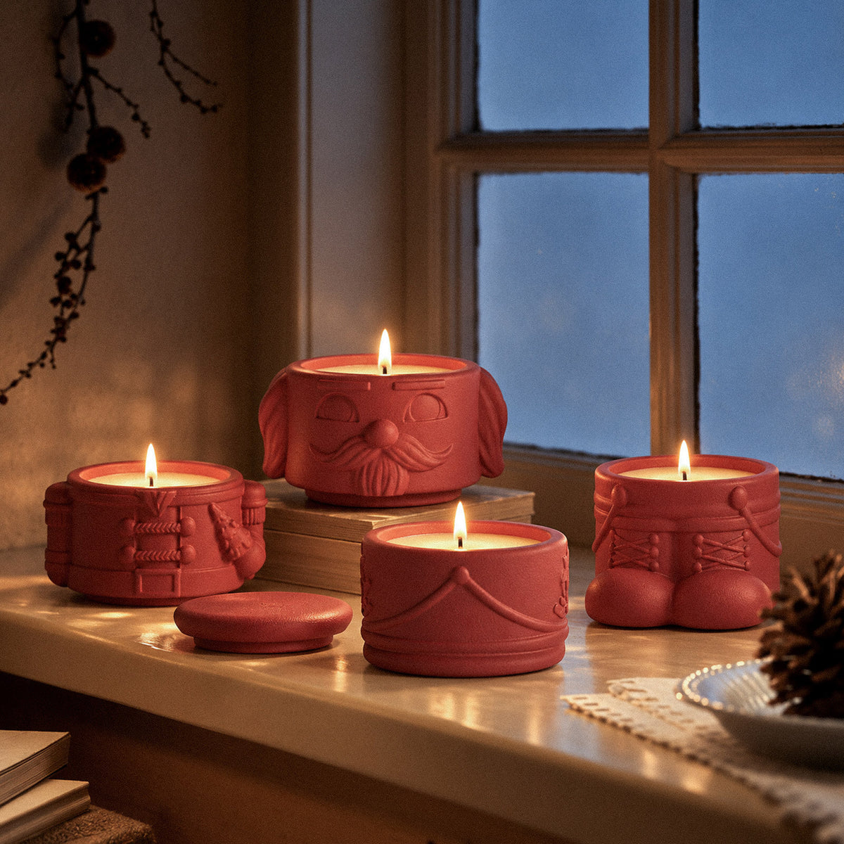 Lit red nutcracker candle jars on a windowsill at dusk