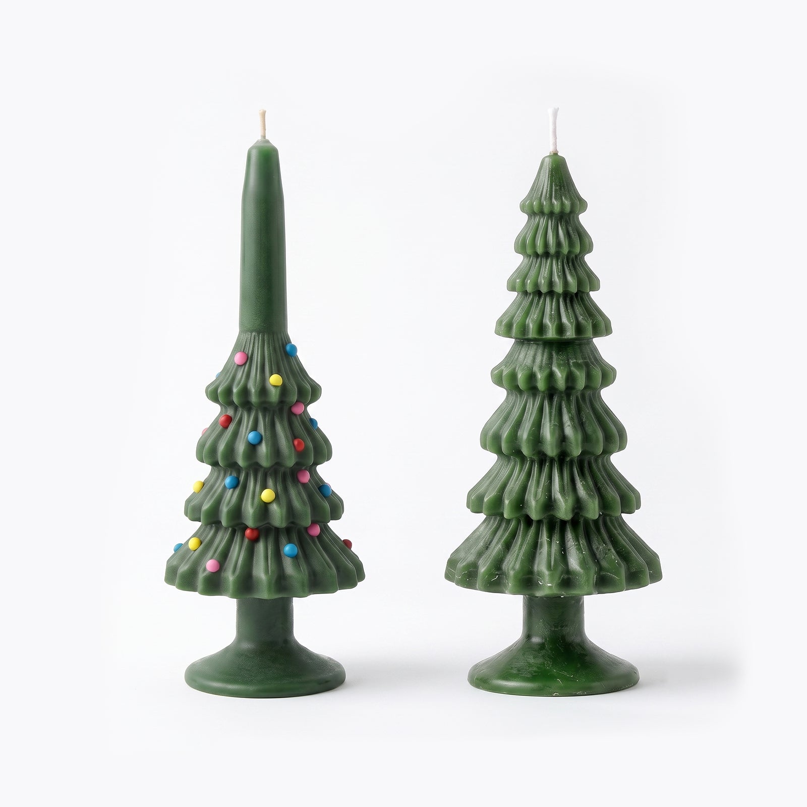 Two Christmas Tree Taper Candles side by side on a white background — one with colorful sprinkle ornaments, one plain green ribbed design.
