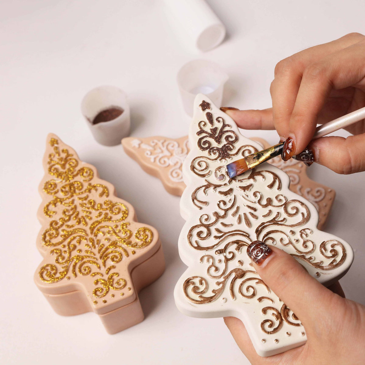 Brushing glitter onto a plaster Christmas tree ornament