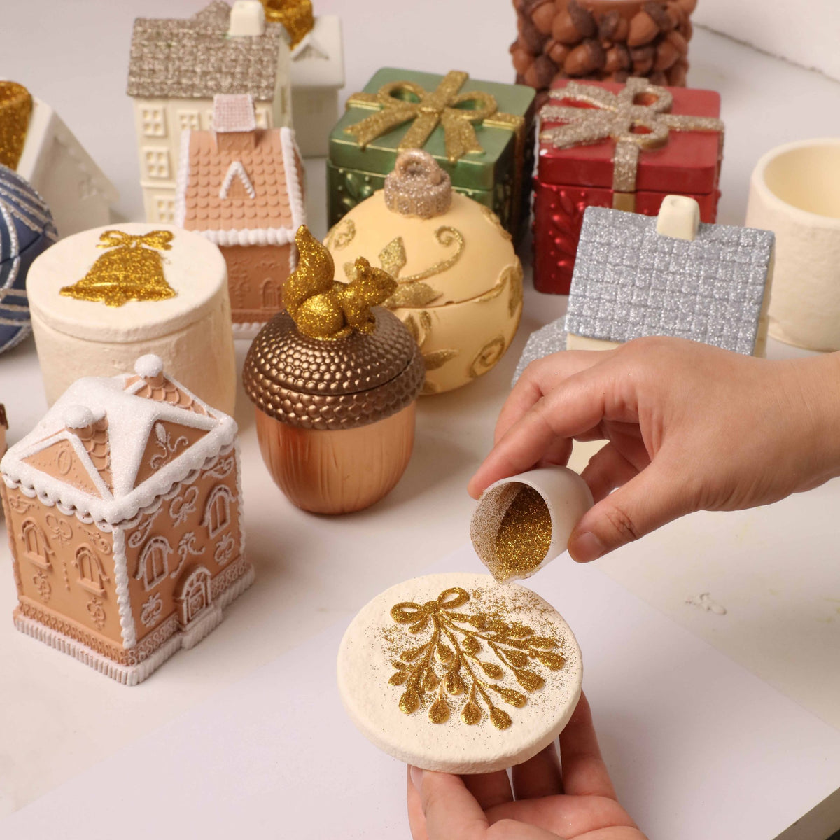 Sprinkling gold glitter over plaster Christmas decorations