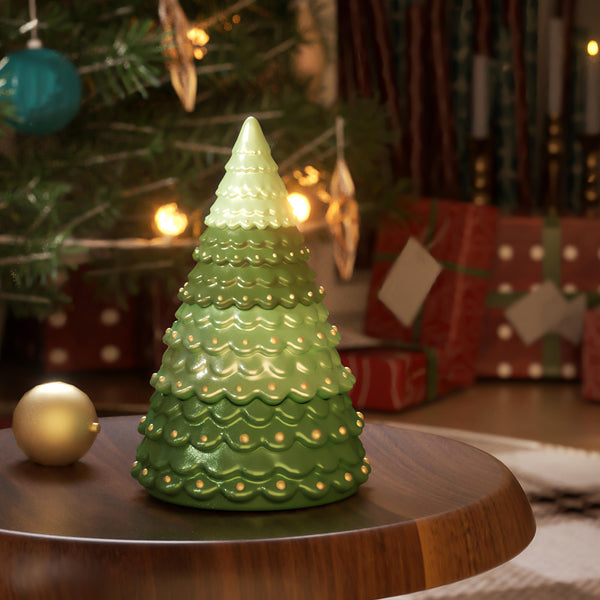 Decorative green Christmas tree-shaped candle jar on a wooden table with festive background