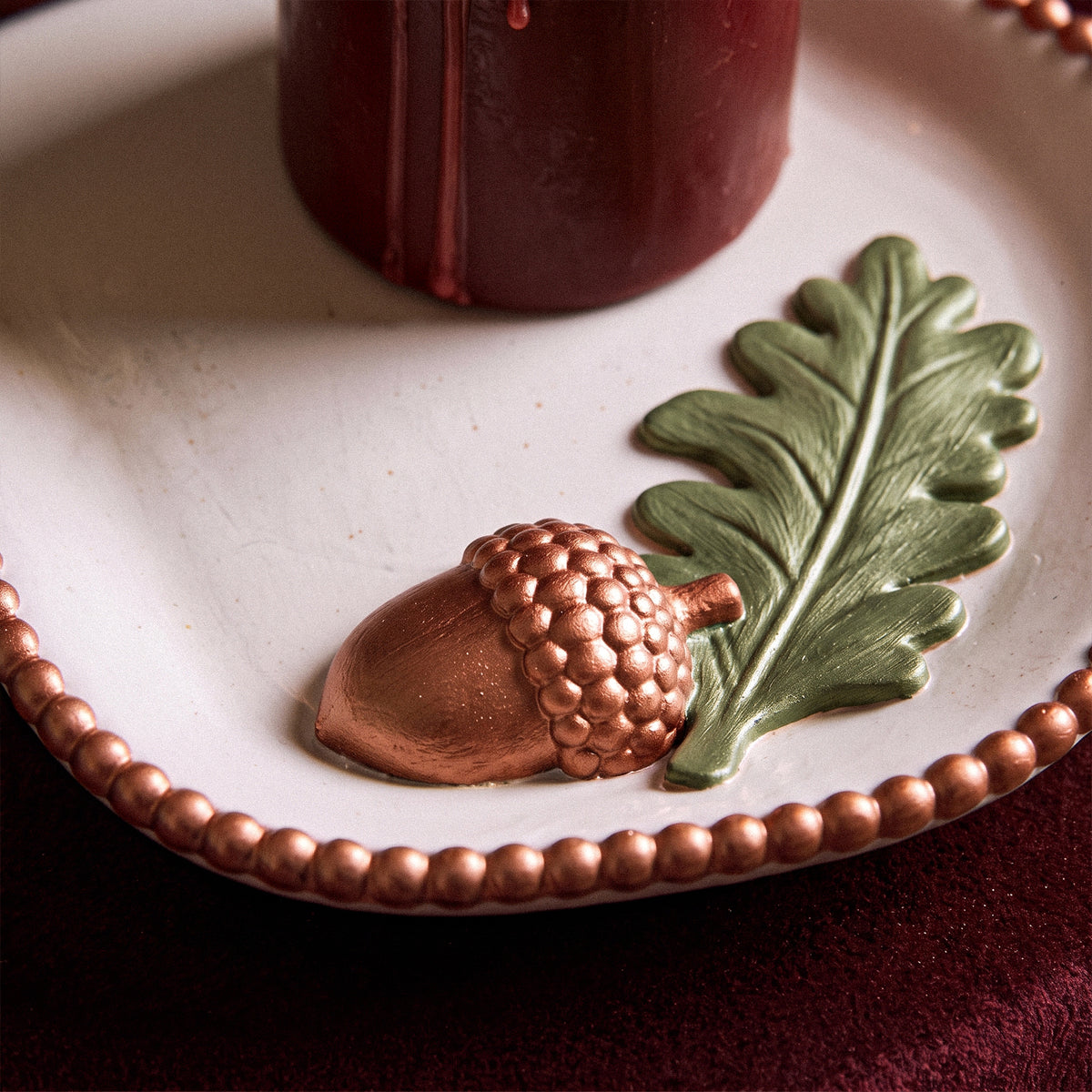 Forest Acorn scalloped trinket tray displayed upright behind a candle