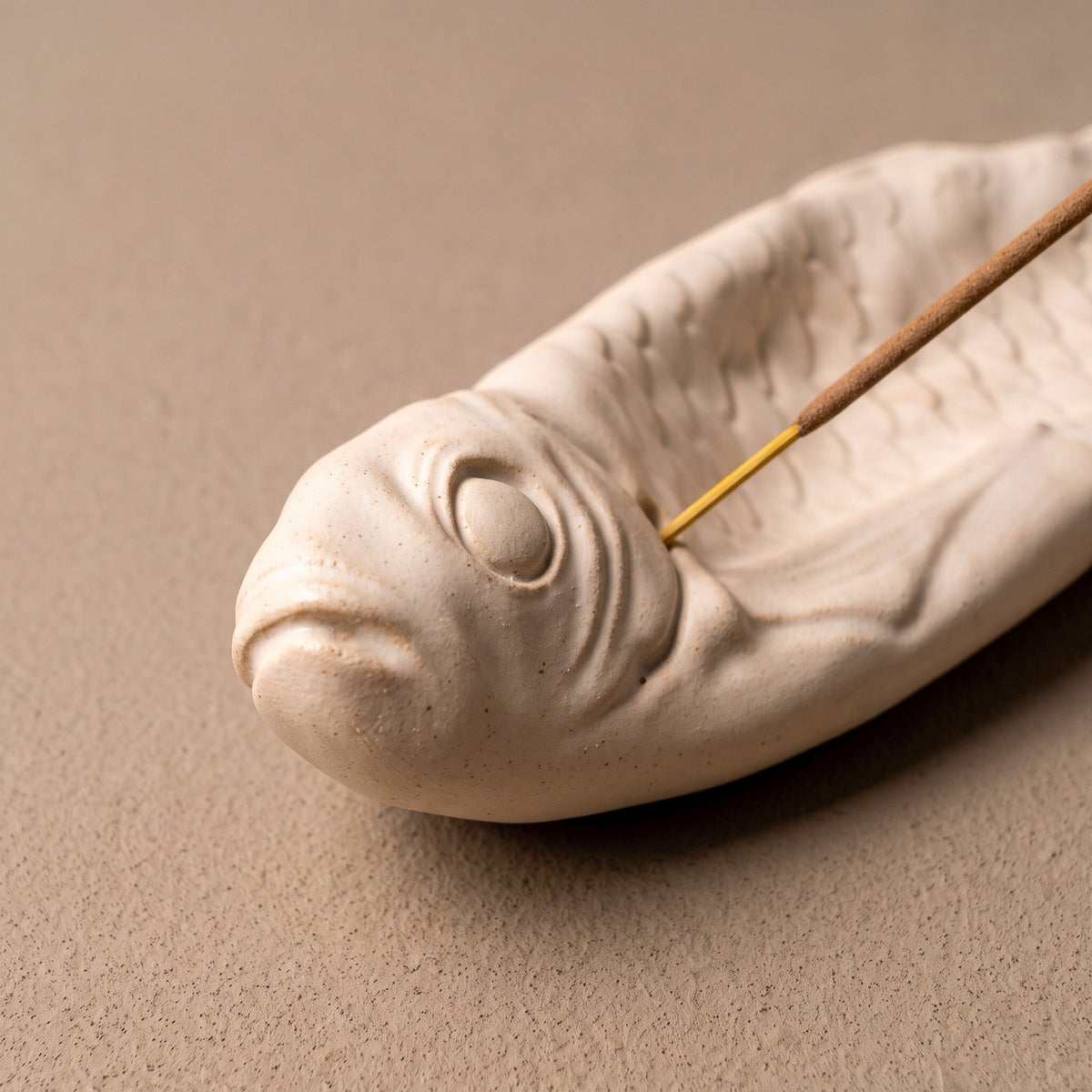Close-up of the sculpted fish head, scales and incense-stick support