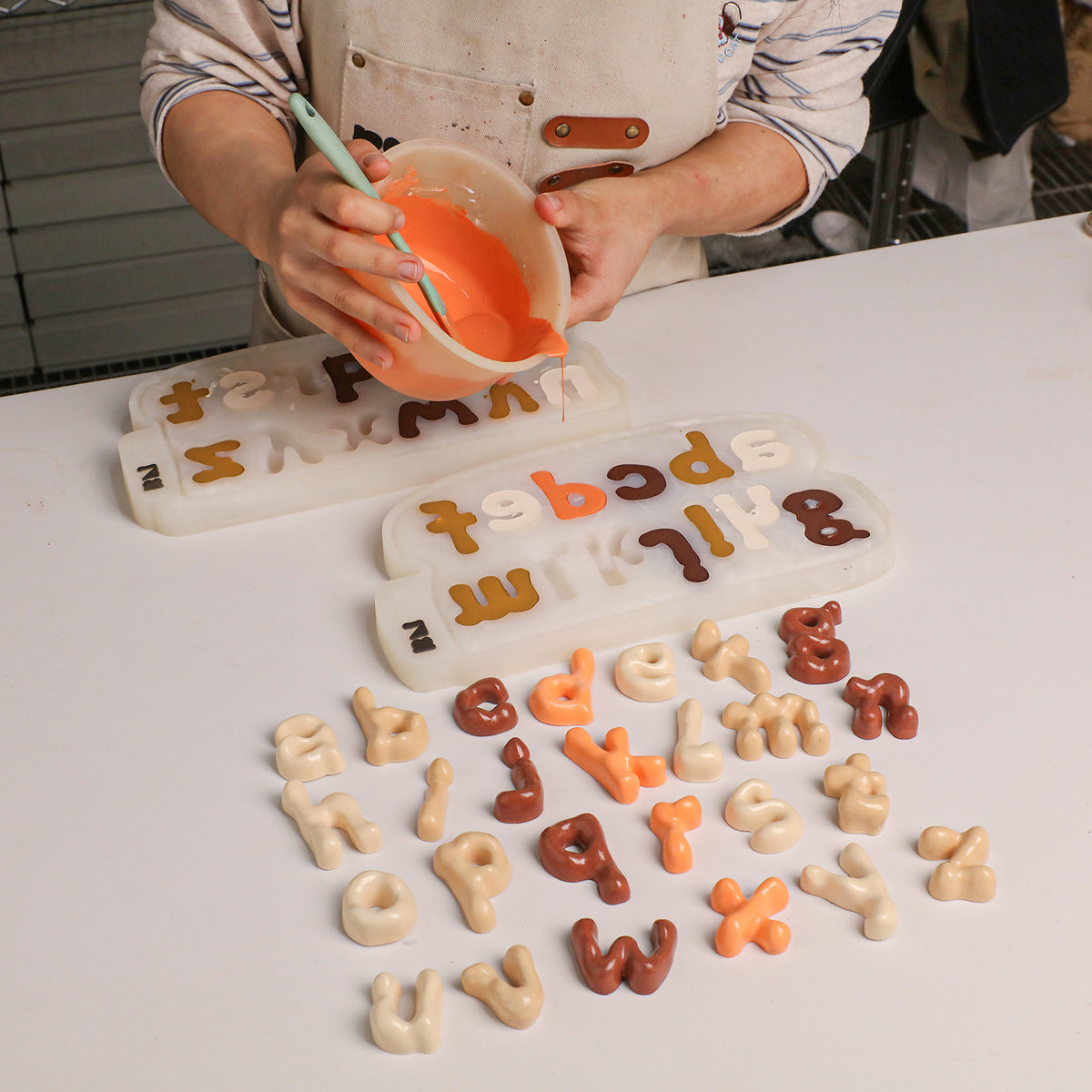 Mixing and pouring casting material beside colourful lowercase letters