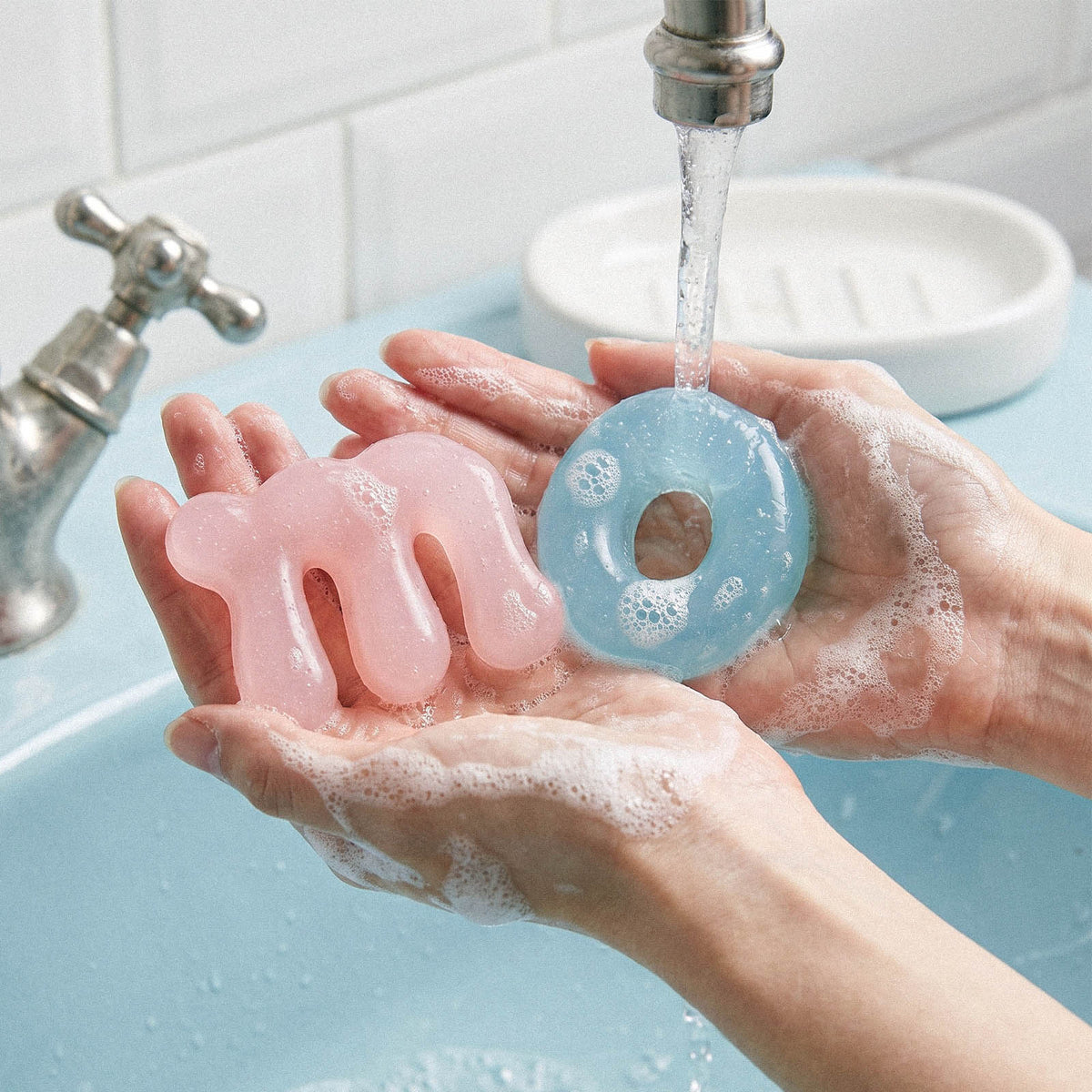 Pink letter m and blue letter o soaps held under running water