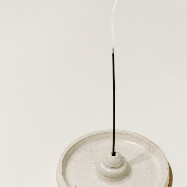 Incense stick in a ceramic holder on a light beige background