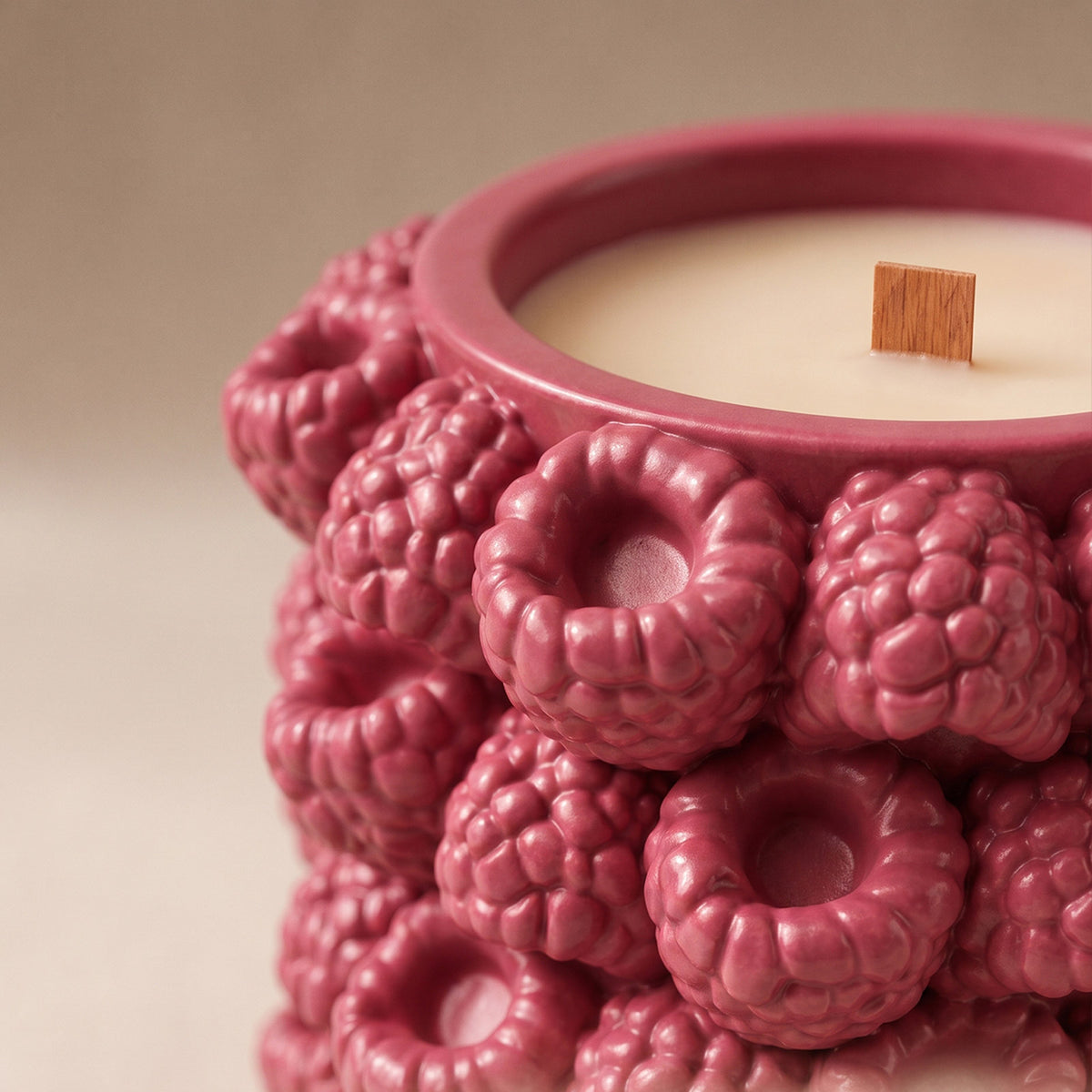 Close-up of the sculpted raspberry relief and rim of a pink candle jar