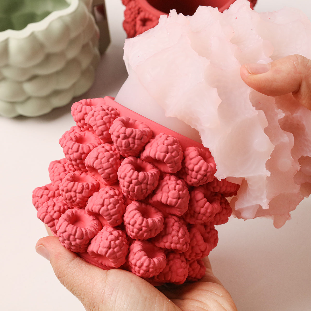 A raspberry-textured jar being released from its flexible silicone mold