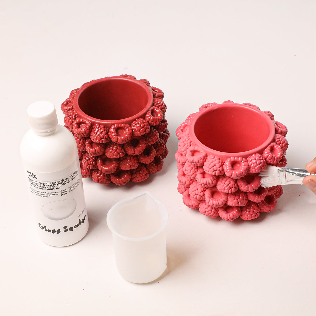 Gloss sealer brushed onto a raspberry candle jar beside sealer and tools