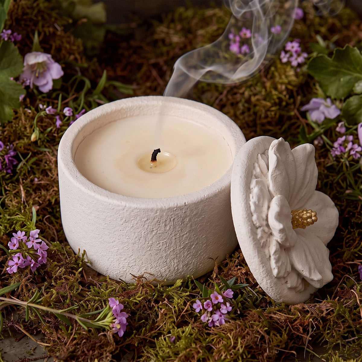 Lit hibiscus candle jar with the flower lid set aside