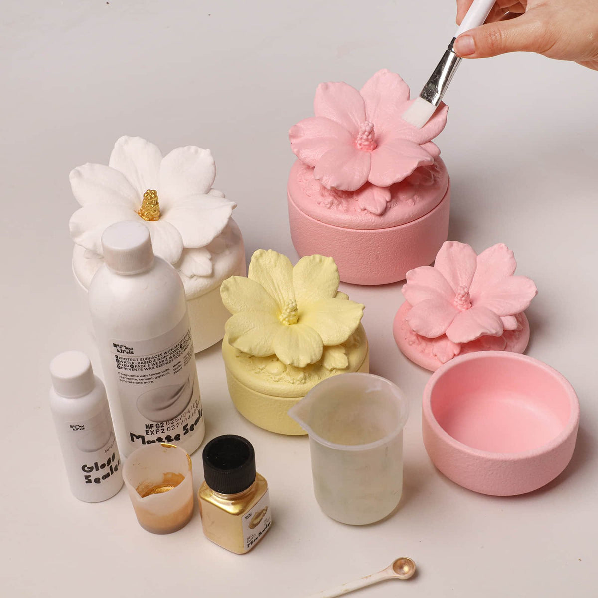 Brushing gold details on finished hibiscus candle jars