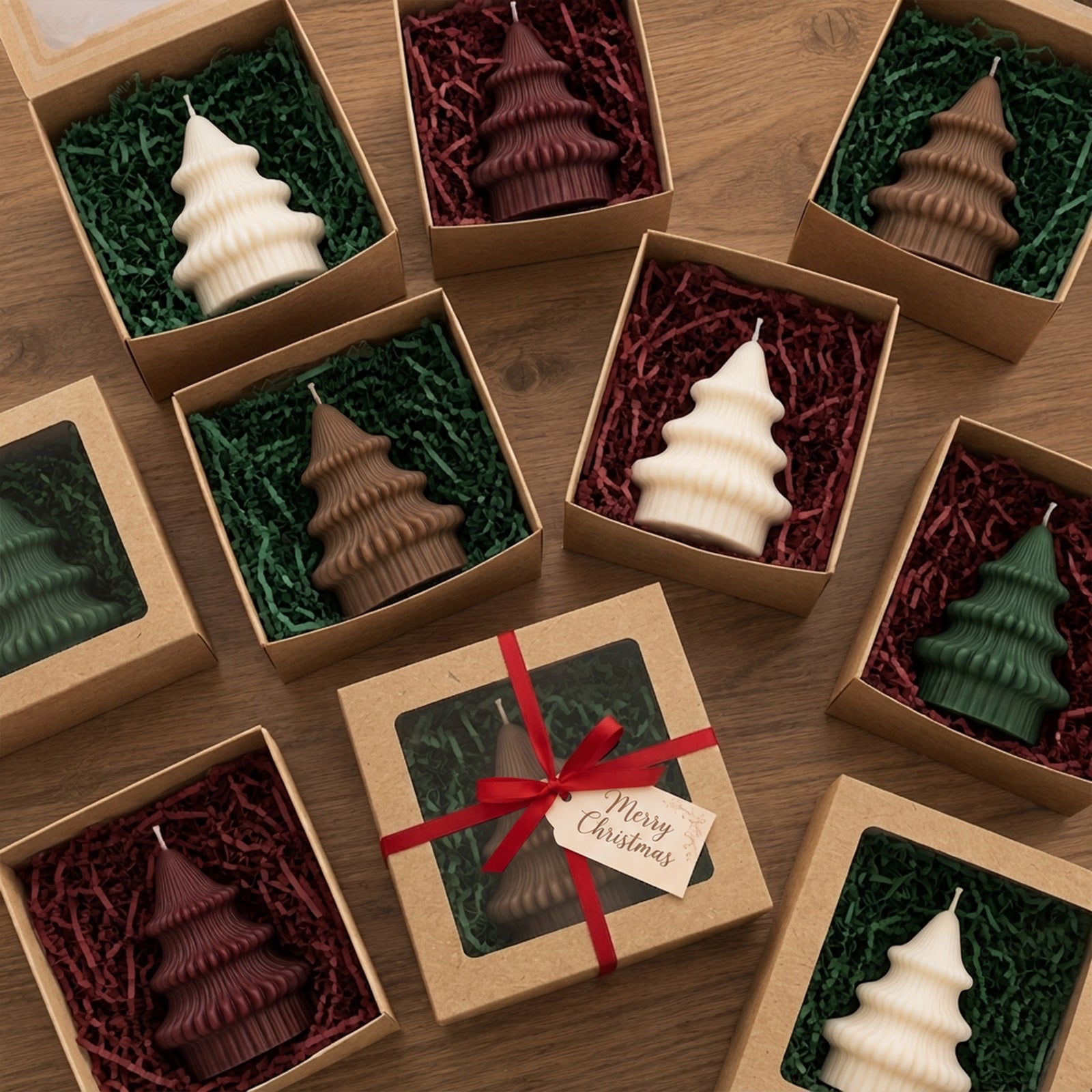 Multiple Sculpted Christmas Tree Candles in ivory, burgundy, brown, and green wax colors, packaged in individual kraft gift boxes with colored paper filler, one tied with a red ribbon and a Merry Christmas gift tag.