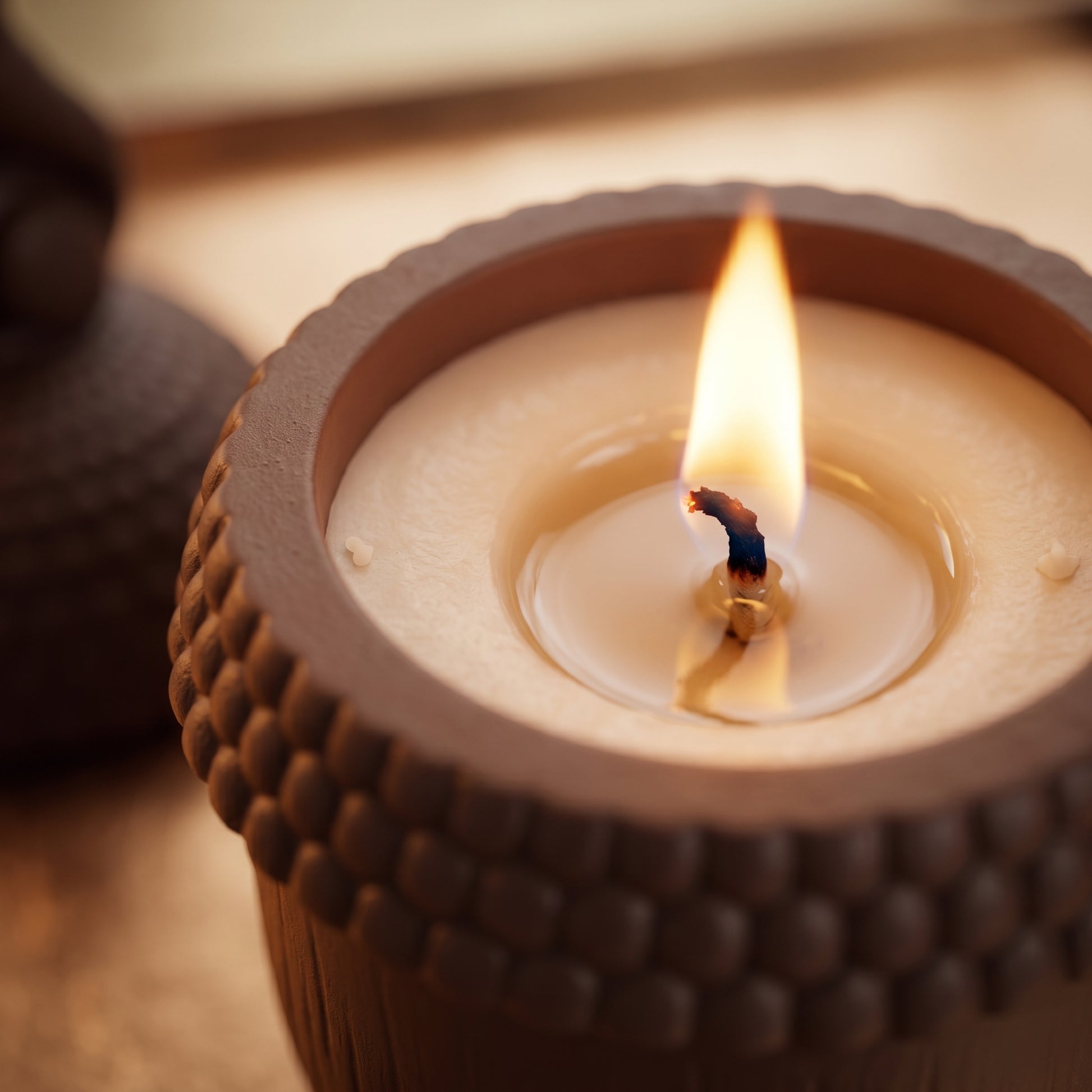 Close-up of a lit candle burning inside the acorn-textured jar.