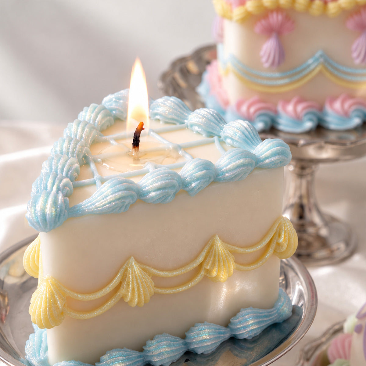 Lit cake candle with blue piped edging and yellow scalloped swags