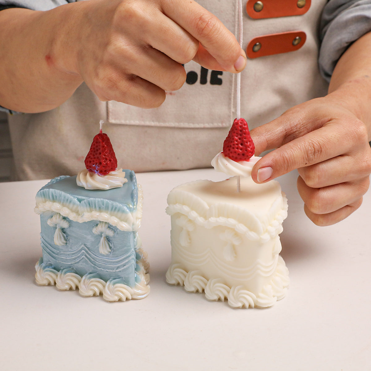 Adding painted details to a strawberry-topped cake candle