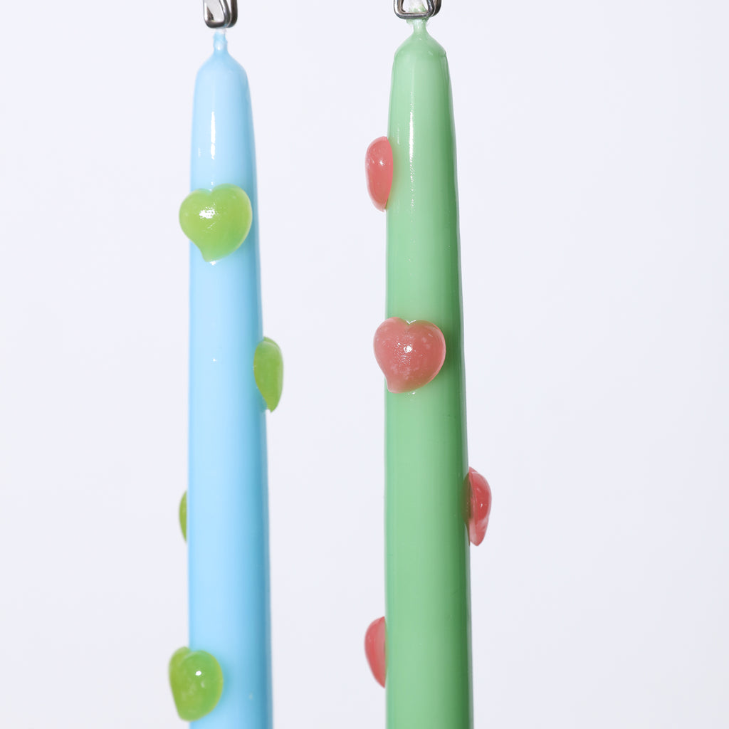 One blue taper candle with green heart accents and one green taper candle with red heart accents hanging from a clip - Boowan Nicole
