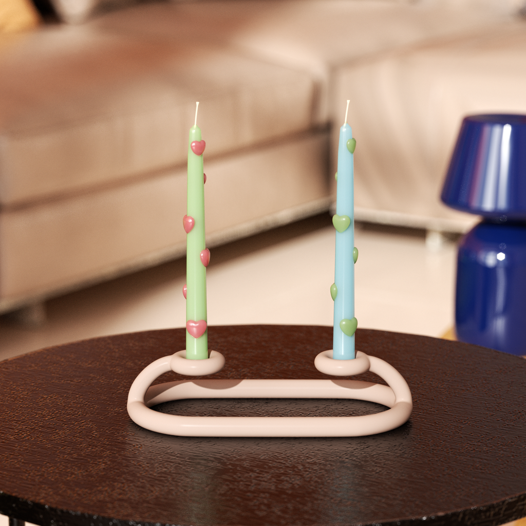 One blue taper candle with green heart accents and one green taper candle with red heart accents on a tabletop curved candlestick-Boowan Nicole