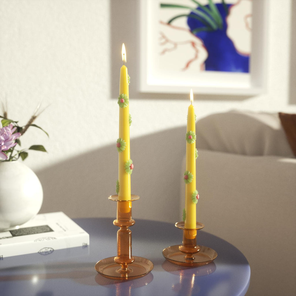 Yellow daisy decorative tapered candle being lit in yellow crystal candle holder on table - Boowan Nicole