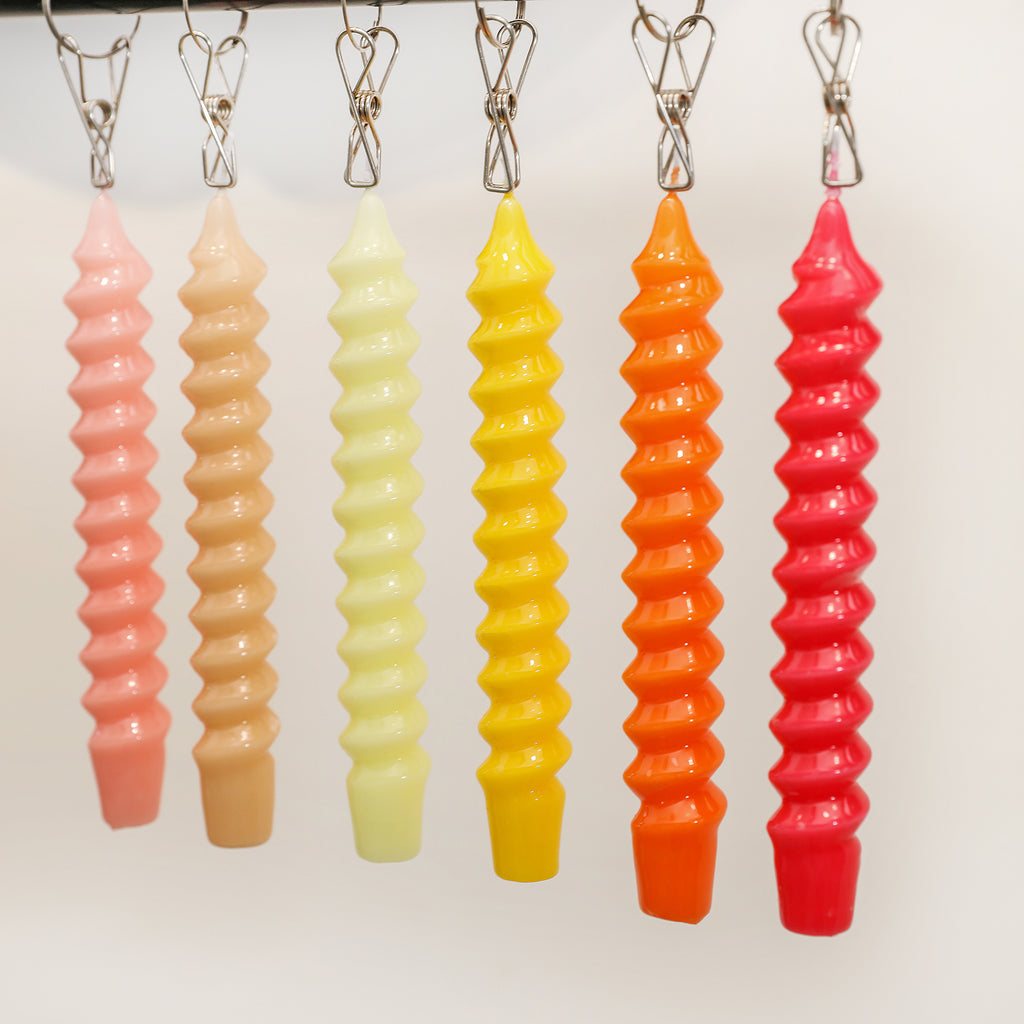 Spiral Taper Candles in different colors are placed on the shelf.
