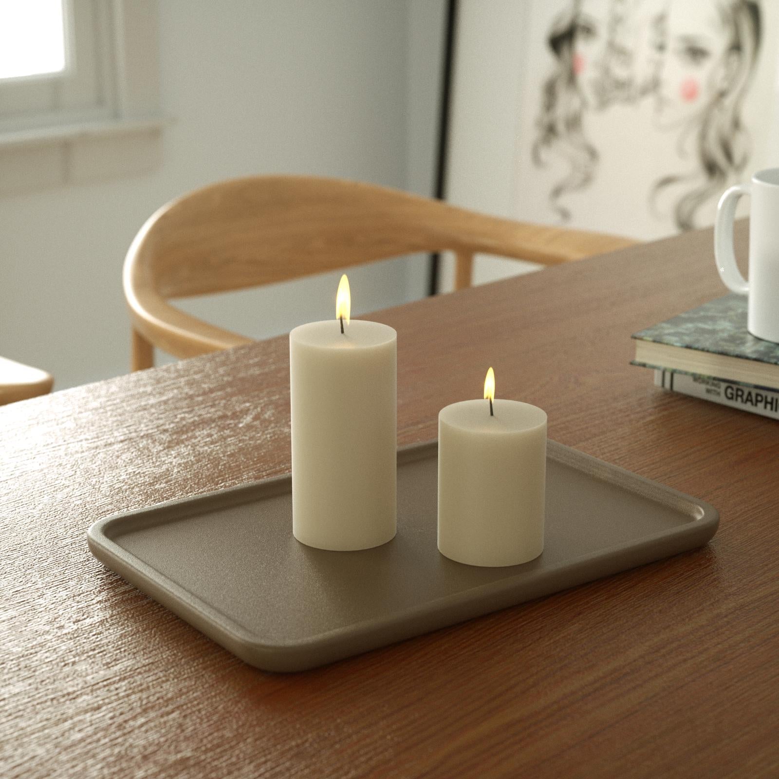 Two slow-burning white cylinder candles sit on a tray on the desk - Boowan Nicole