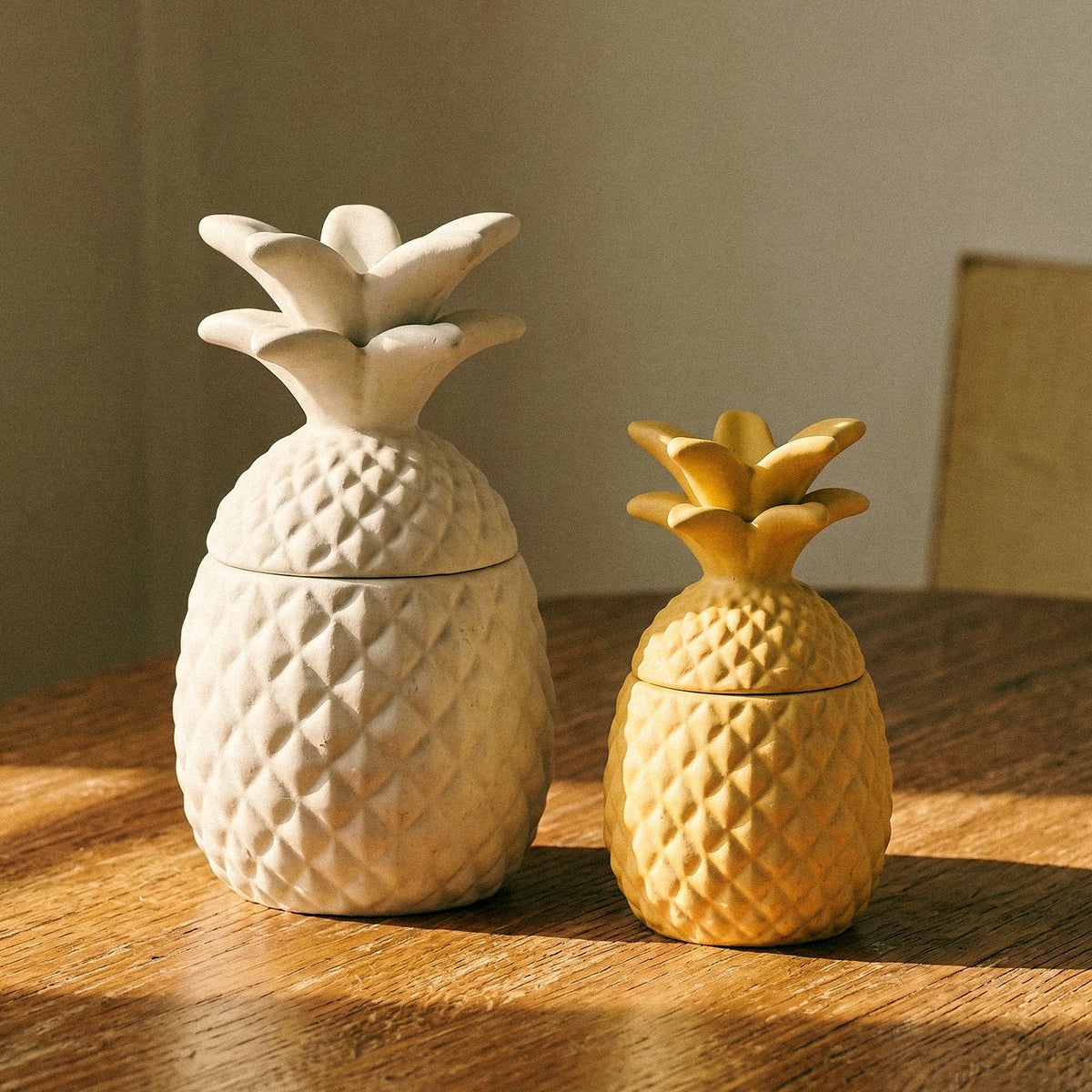 Tropical pineapple candle jars in white and yellow on a wooden table