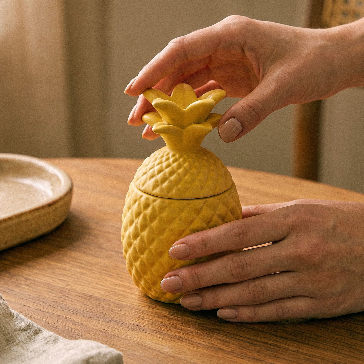 Lifting the pineapple lid off a yellow candle jar