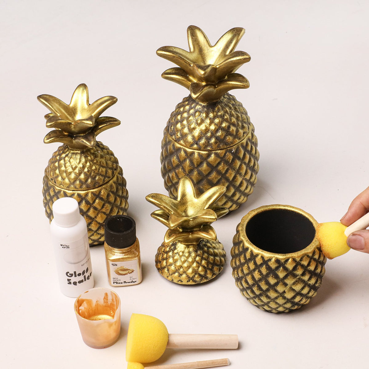 Gold-painted pineapple candle jars with sealer and sponge brushes