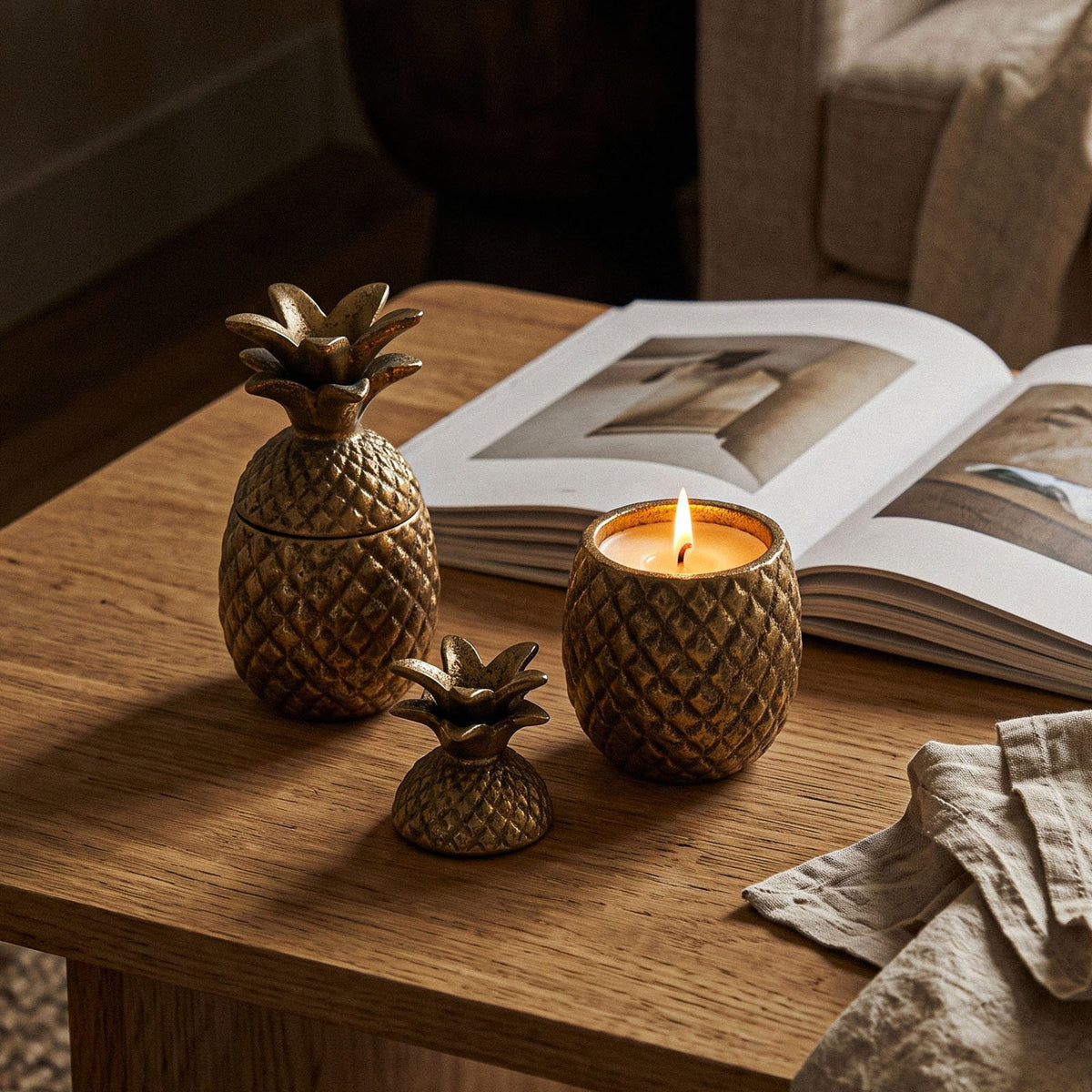 Gold pineapple candle jars on a wooden side table