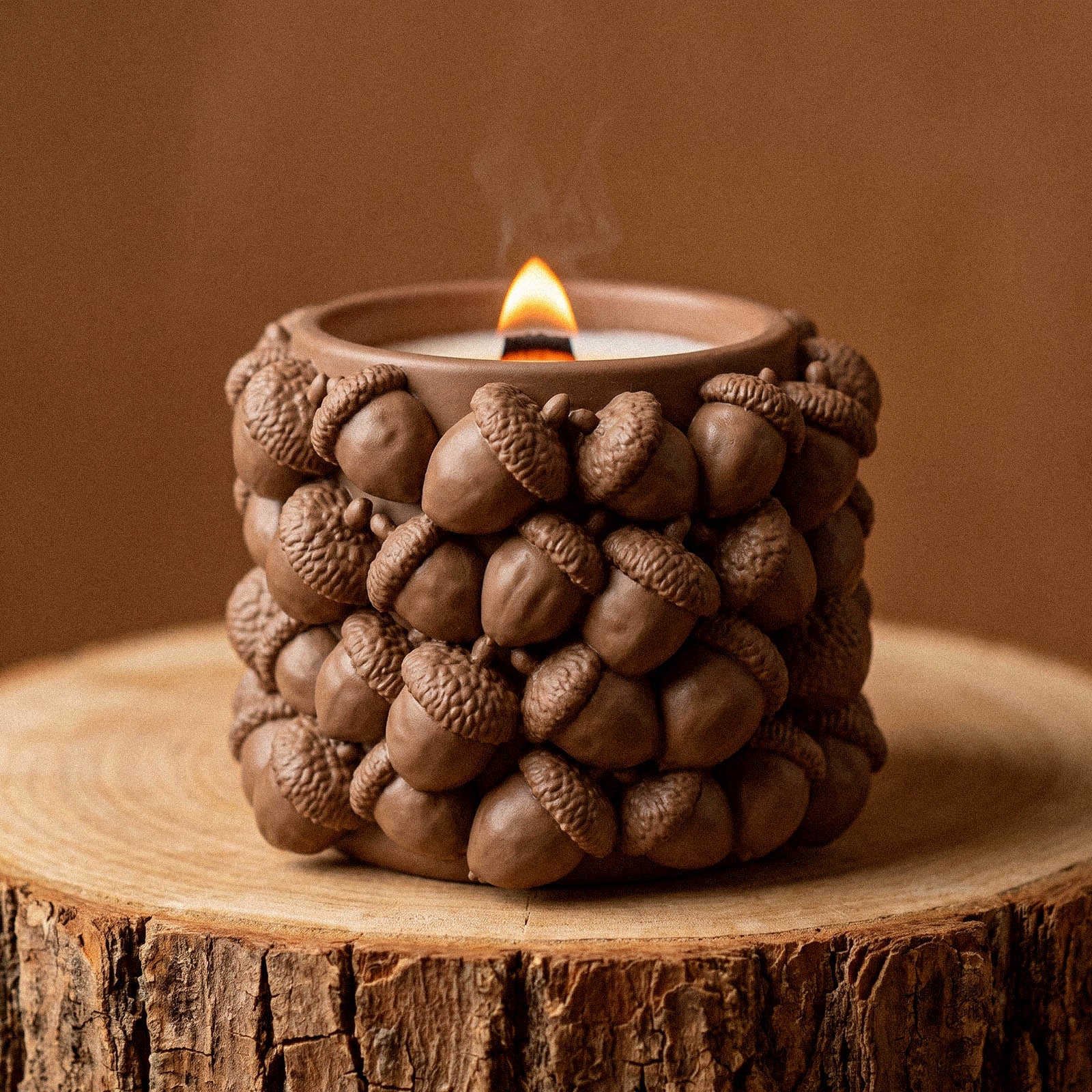 A woodland acorn candle jar silicone mold candle, densely covered in realistic acorn clusters, burning with a wooden wick against a warm brown backdrop.