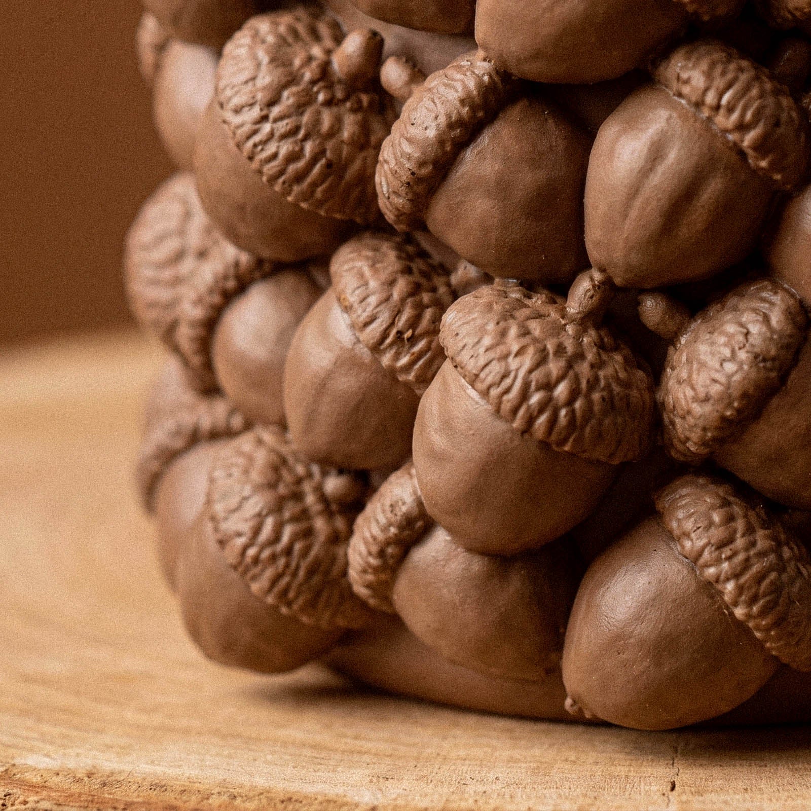 Macro close-up of layered acorn caps and nuts molded into the side of a silicone candle jar mold.