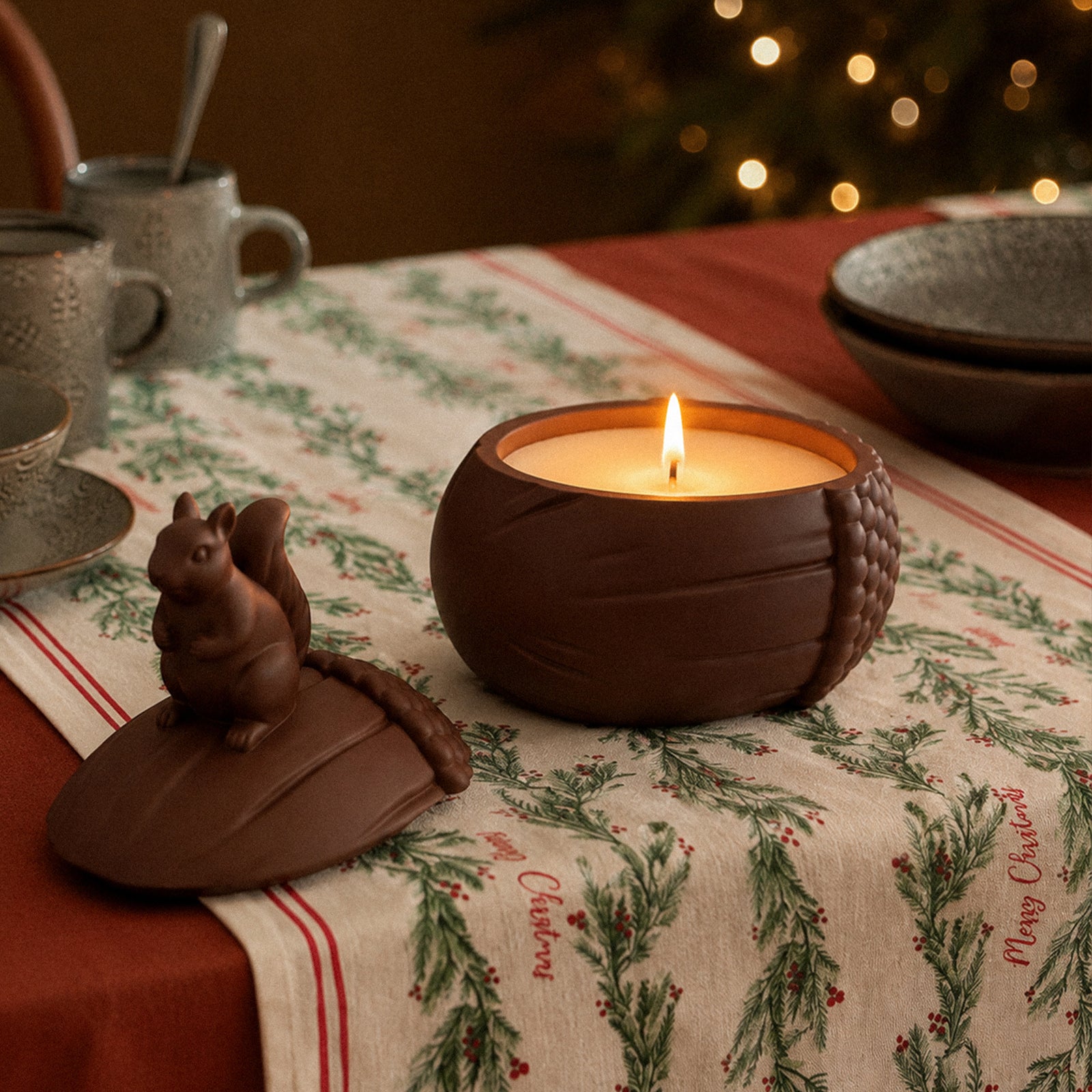 Lit candle inside the Woodland Nut Squirrel acorn jar with the squirrel-topped lid removed and placed beside it