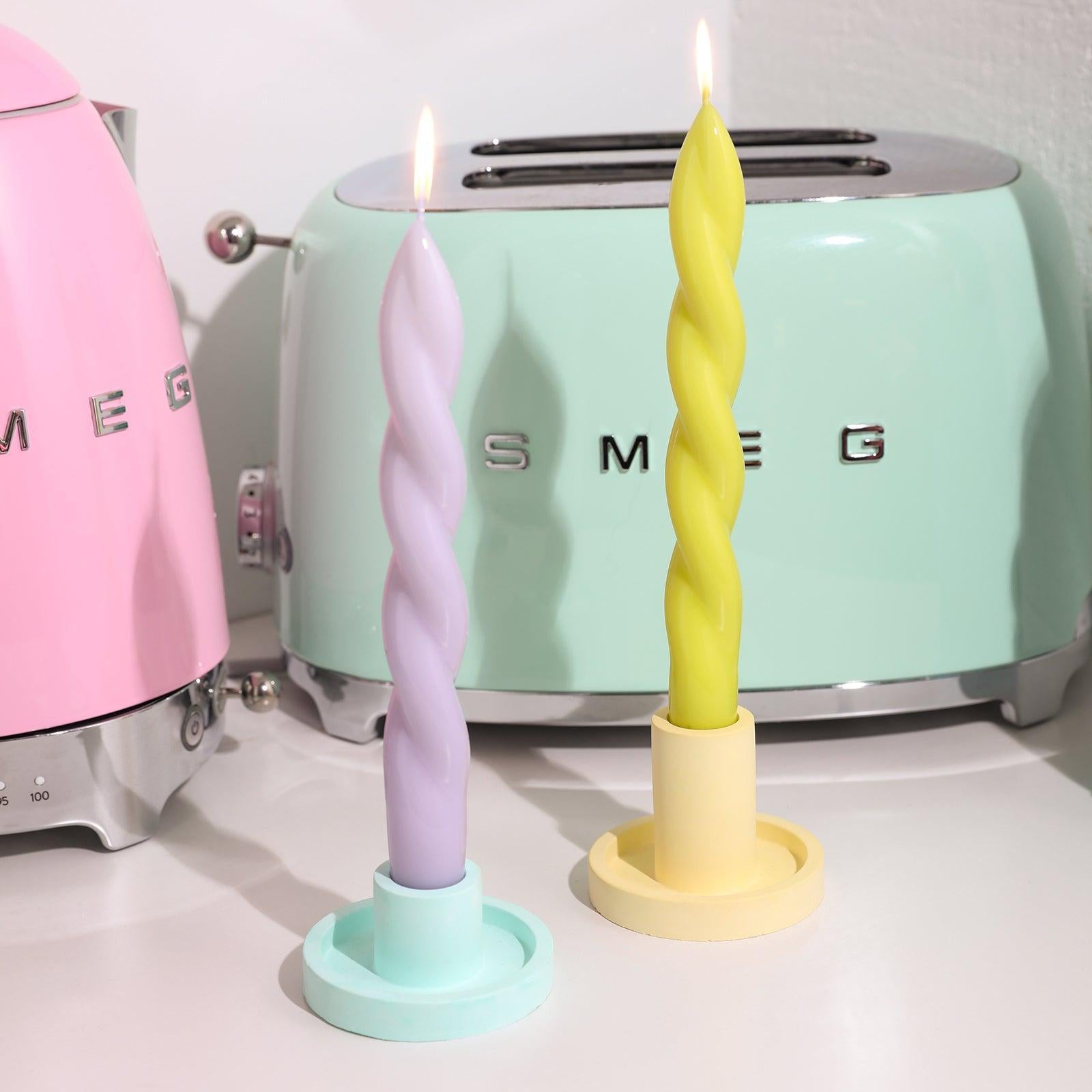 Two lit spiral candles elegantly placed on a candle holder.