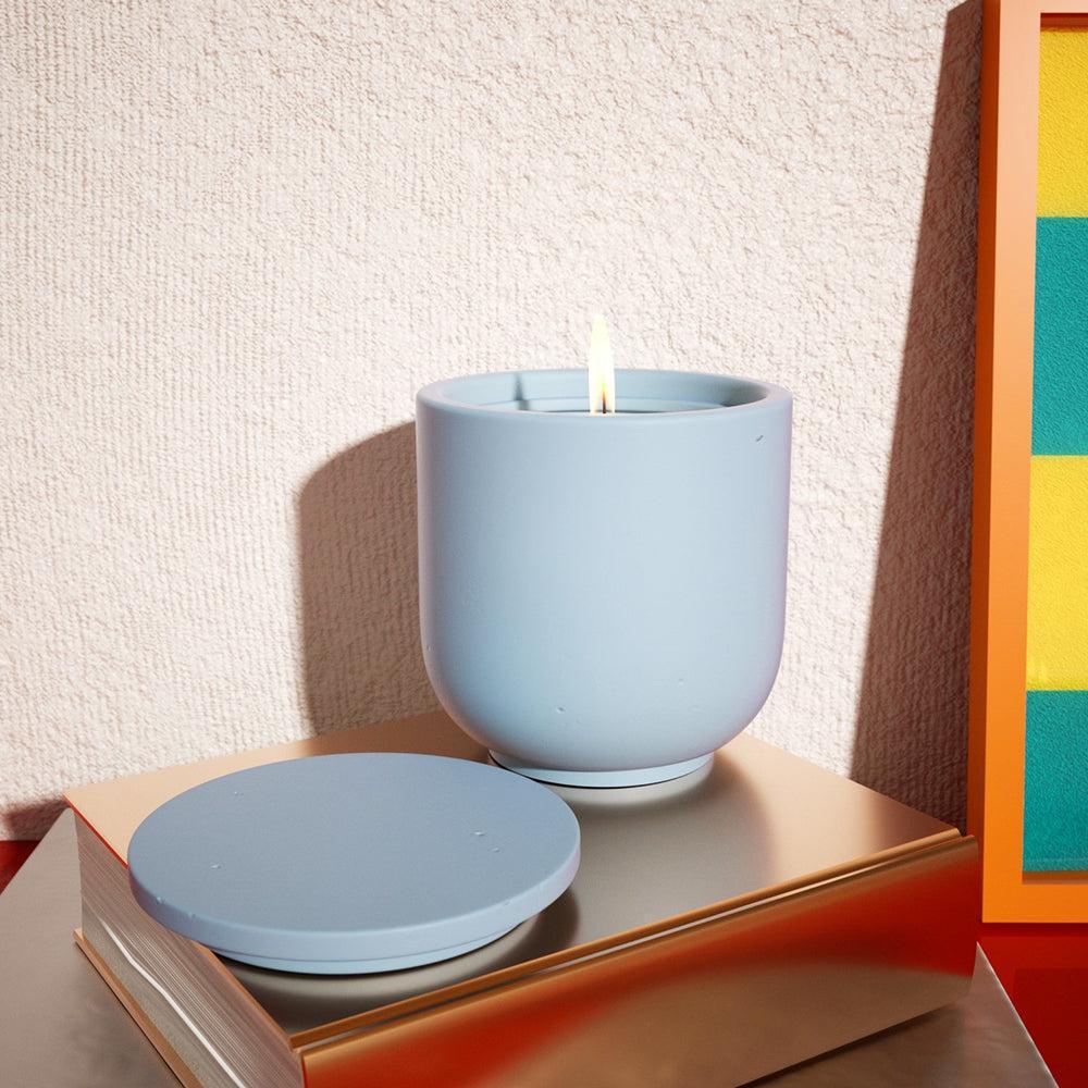 Blue candle jar being lit, placed on a book, a moment illuminated with Boowannicole's essence.