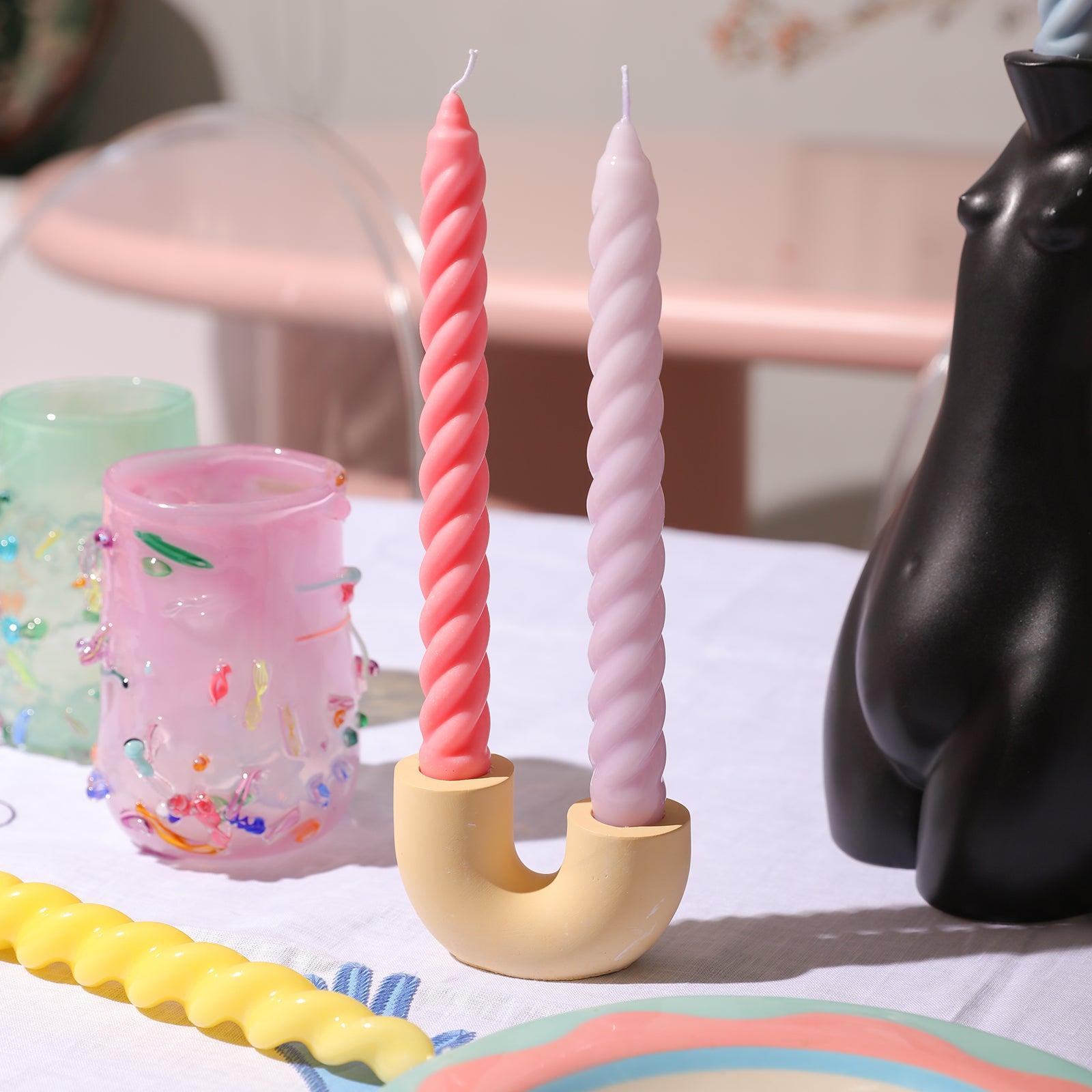 Two candles crafted with Boowannicole's silicone molds elegantly positioned on a candle holder made from Boowannite material.