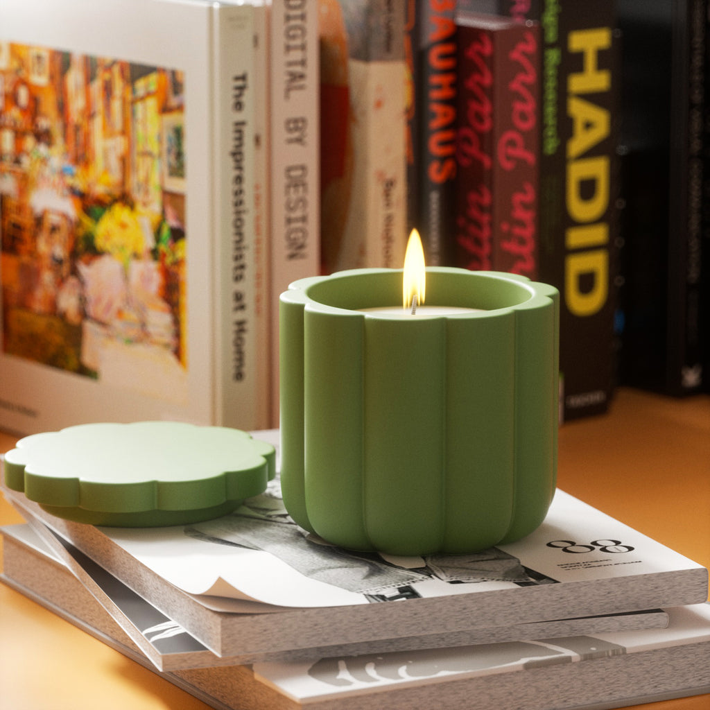 A candle gracefully burns inside a candle jar, resting atop a stack of artfully arranged books