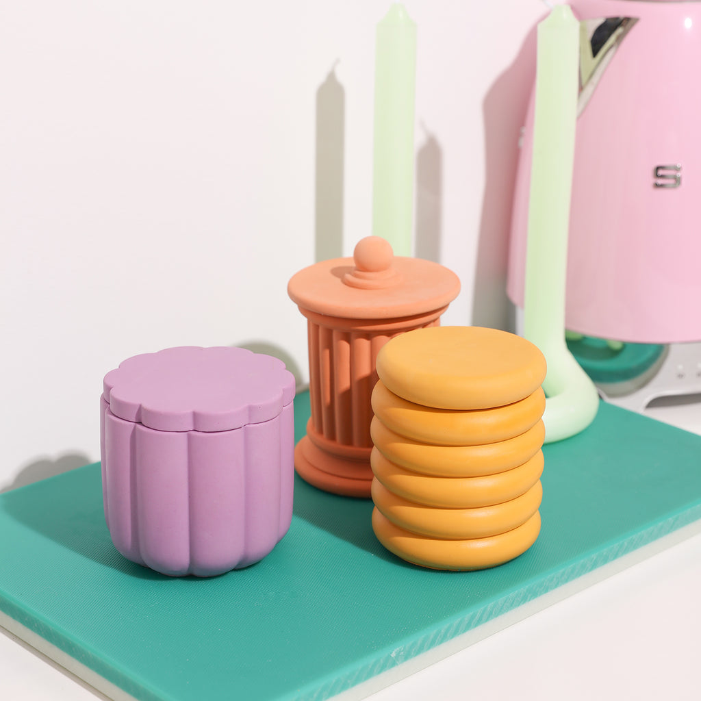 Three candle jars of distinct colors harmoniously displayed together. Boowannicole's design, vibrant in hues, adds a colorful and unique touch to the space.