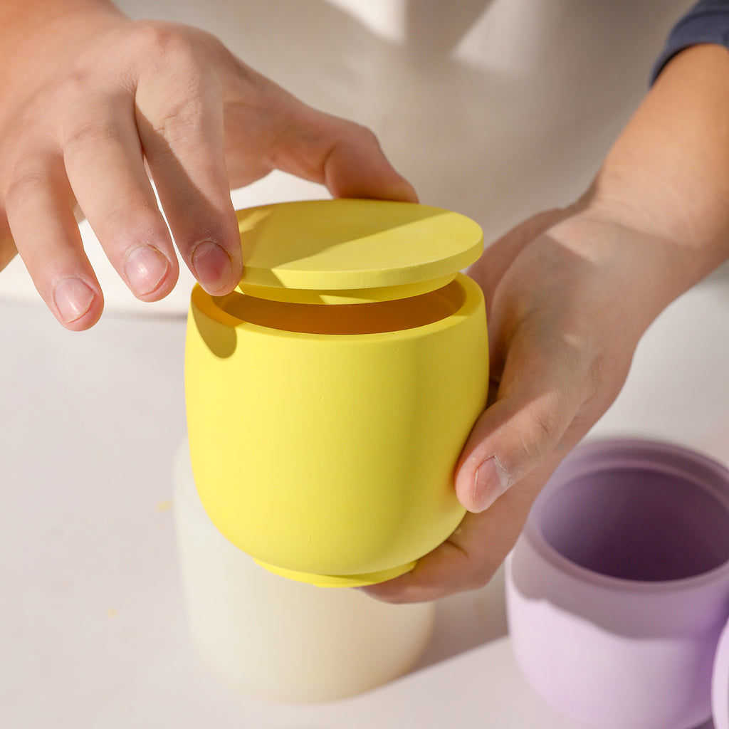Boowannicole's yellow candle jar showcased in hand, its lid gently unveiling in a mesmerizing moment.
