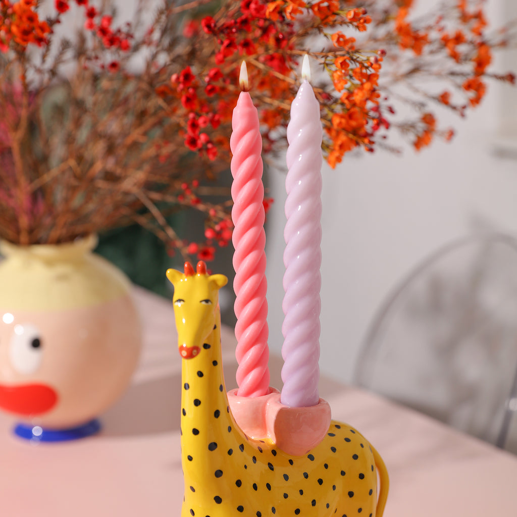 After being lit, two candles crafted with Boowannicole's touch rest atop a giraffe-shaped candle holder