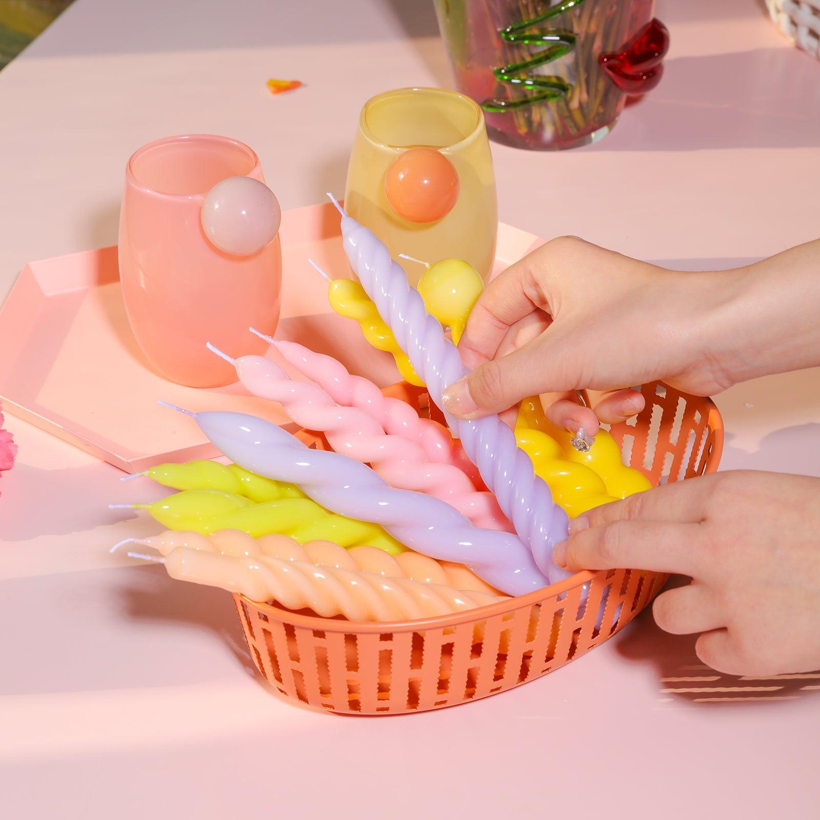 Taper candles crafted with Boowannicole silicone molds delicately rest in a plastic basket. 