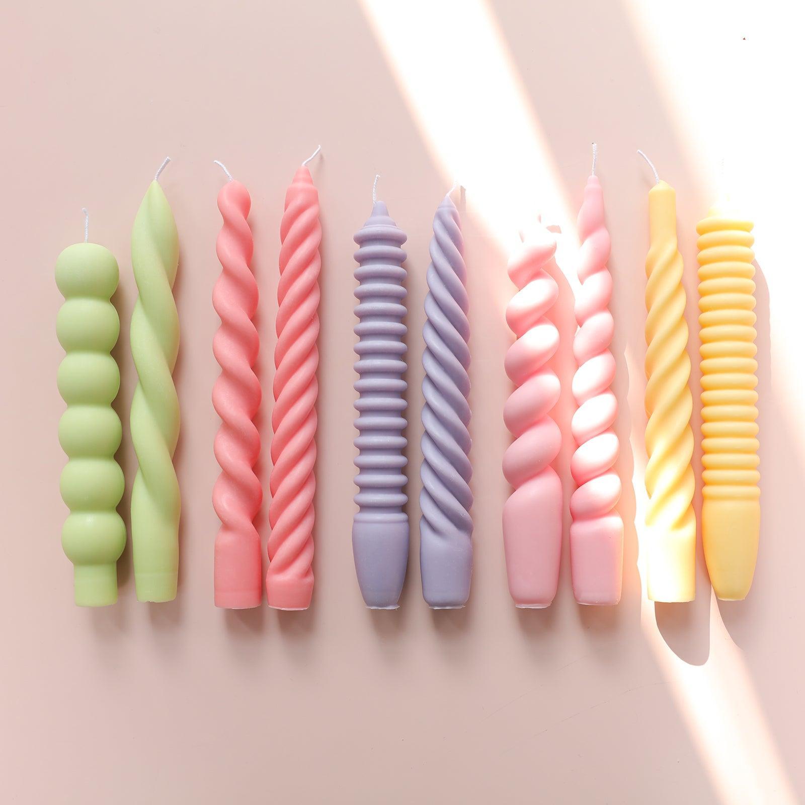 Candles of varied colors and shapes, crafted with Boowannicole's silicone molds, elegantly adorn the tabletop with artistic flair.