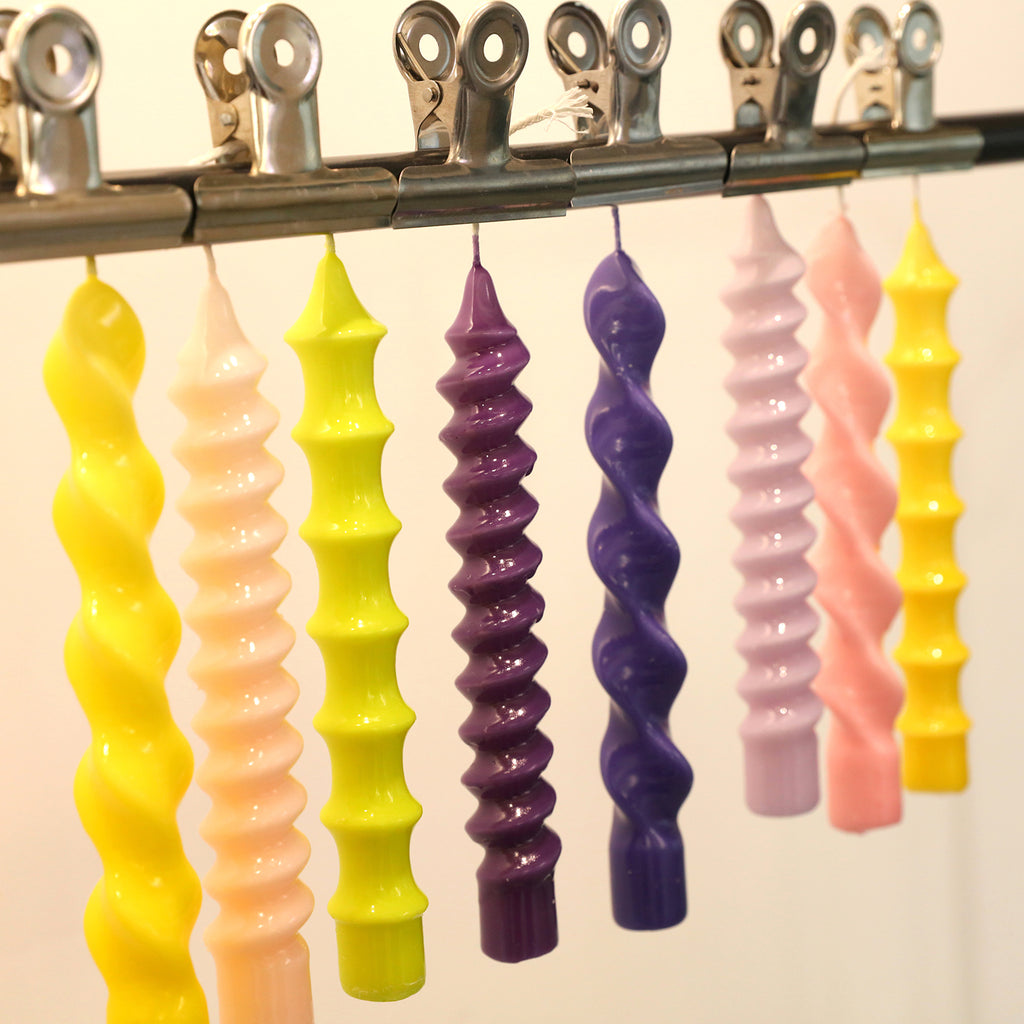 Taper candles crafted with Boowannicole's silicone molds hanging on a rod.