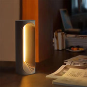 Set the mood with the warm glow – a concrete table lamp illuminates a dimly lit room, casting a soothing light on the desktop.