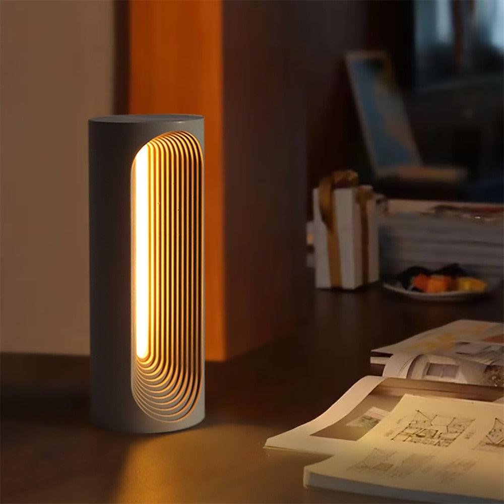 Set the mood with the warm glow – a concrete table lamp illuminates a dimly lit room, casting a soothing light on the desktop.