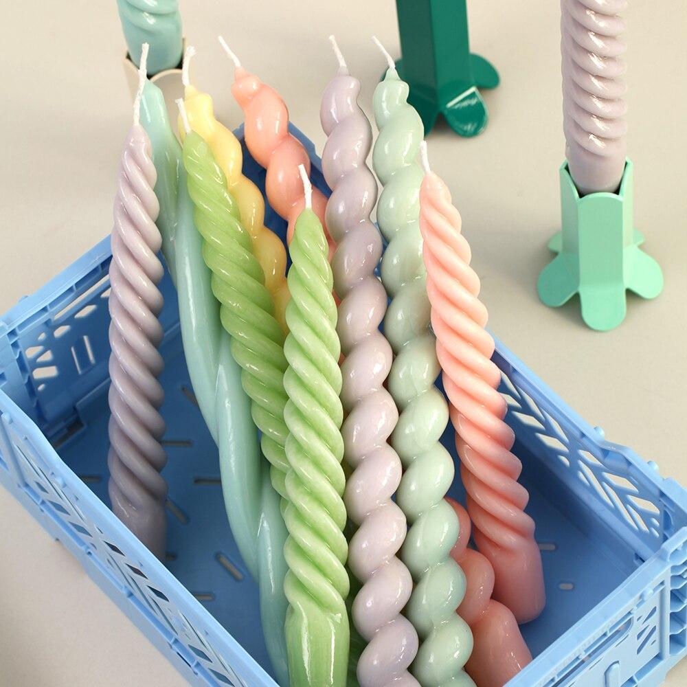 Spiral taper candles in various colors and designs, crafted with Boowannicole silicone molds, elegantly placed in a basket.